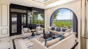 A spacious living area with a large arched window offering a view of the outdoors, a modern ceiling design, and a mix of seating arrangements. - Eastin Hotel Vientiane Laos (Vientiane)