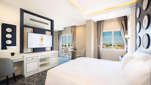 Une chambre d’hôtel avec un grand lit, un bureau avec un ordinateur, une chaise et une vue sur la ville par la fenêtre.