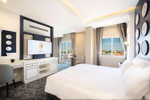 Camera d'albergo con un letto grande, una scrivania con un computer, una sedia e vista sulla città dalla finestra.