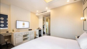 Une chambre d’hôtel équipée d’un lit, d’un bureau, d’une télévision et d’une armoire.