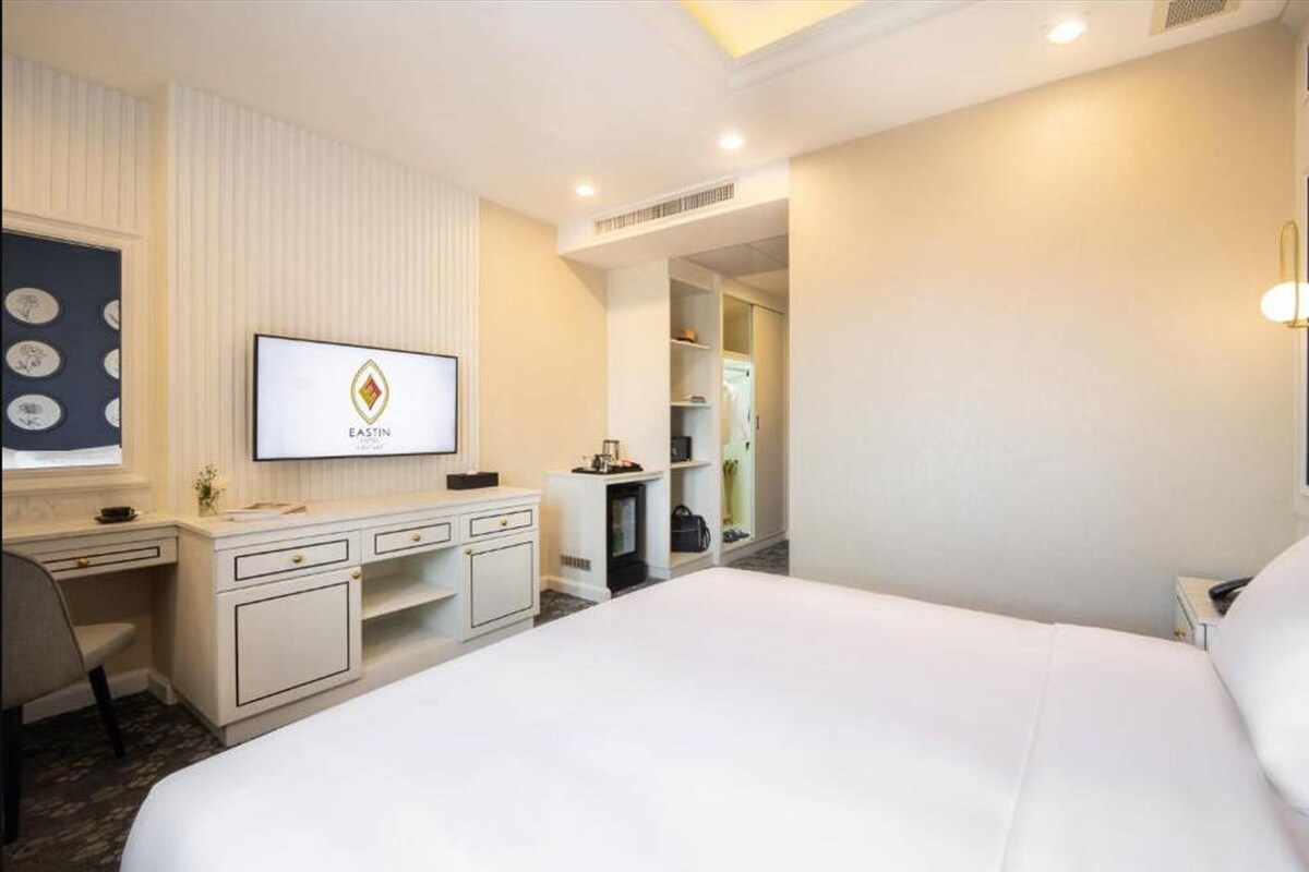 A hotel room with a bed, a desk, a TV, and a wardrobe.