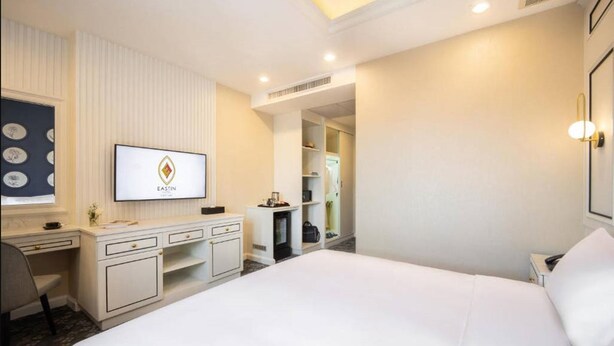 Una habitación de hotel con cama, escritorio, televisor y armario.