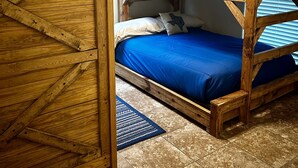 Une chambre avec un lit superposé en bois, une armoire en bois et un drapeau du Texas accroché au mur.
