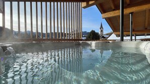 A hot tub with a clear view of a mountain landscape and a church steeple in the background. - Chalet (LA VALLE)