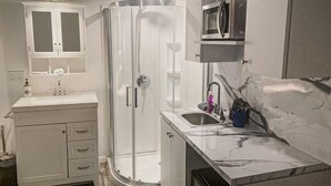A modern bathroom with a shower enclosure, a sink with a countertop, and a cabinet above the sink. - Miramar Breeze (Miramar)