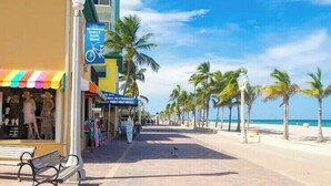 A beachside promenade with shops, a bench, and palm trees. - Miramar Breeze (Miramar)