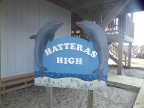 A sign with two dolphins and the text "Hatteras High" on a wooden structure.