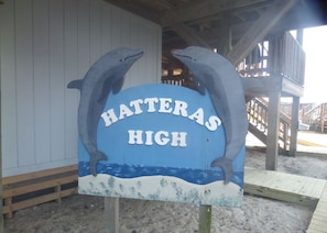 A sign with two dolphins and the text "Hatteras High" on a wooden structure.