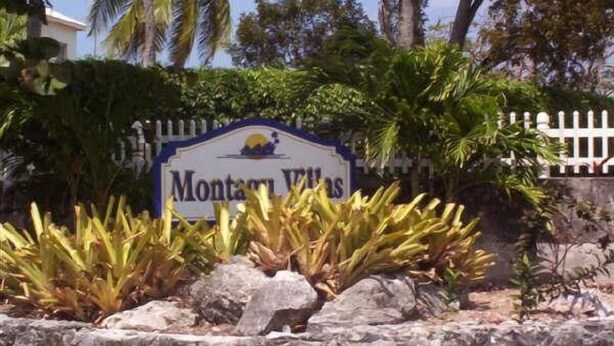 A sign for 'Montana Villas' with a white picket fence and tropical plants. - Tangerine Sunsets Tangelo (Nassau)