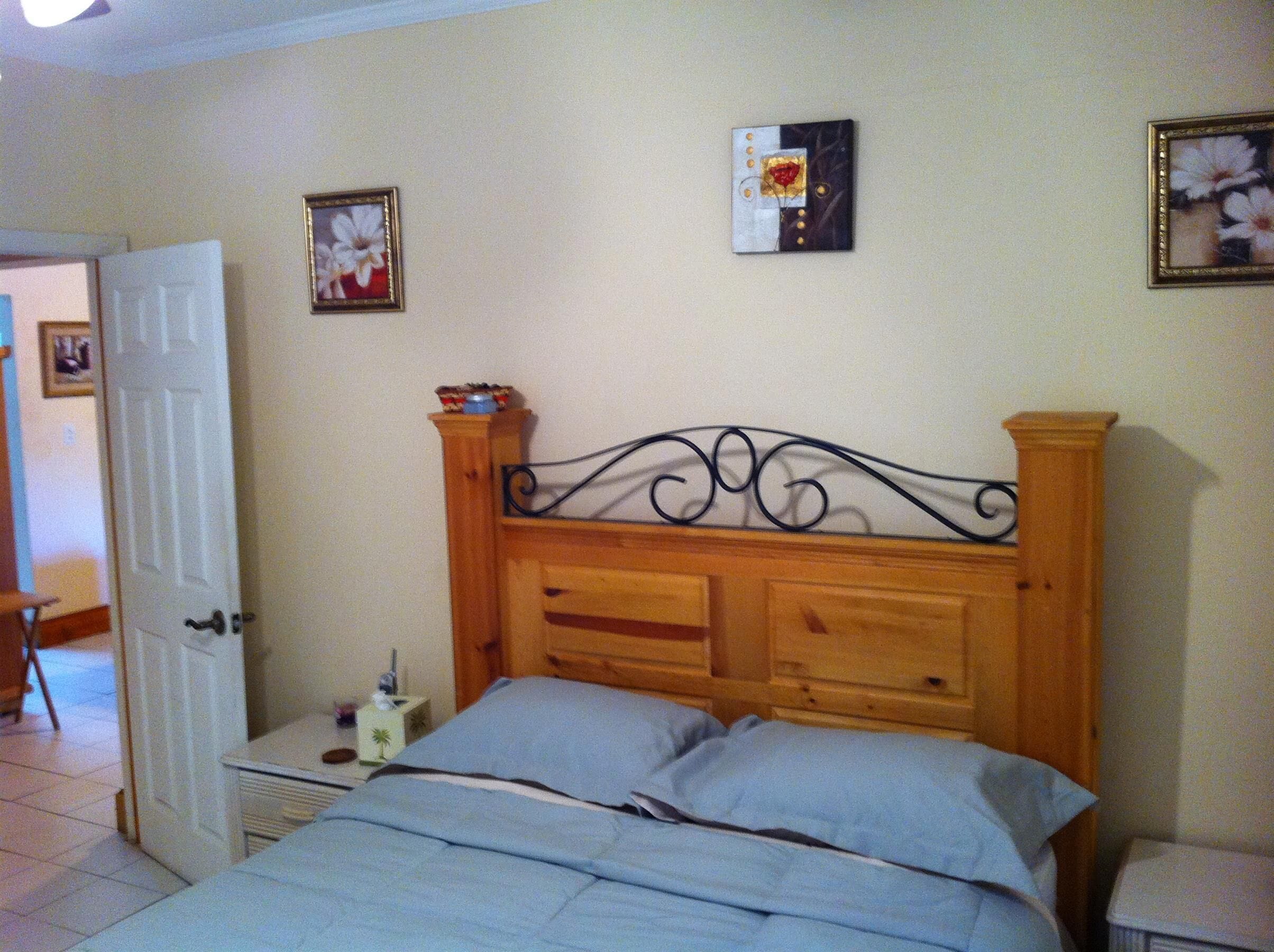 A bedroom with a wooden bed, a nightstand, a door, and two wall-mounted pictures.