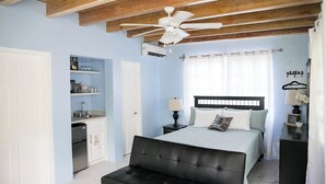 Un dormitorio con cama, mesita de noche y ventilador de techo.