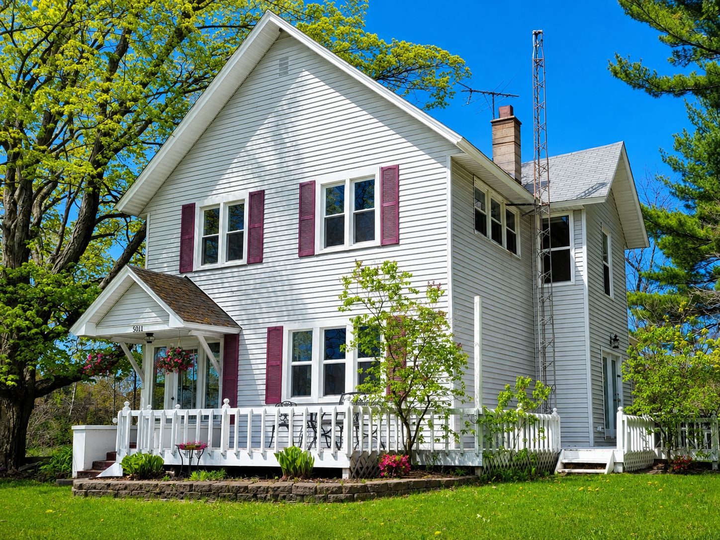 A two-story house with a porch, white siding, and red shutters.