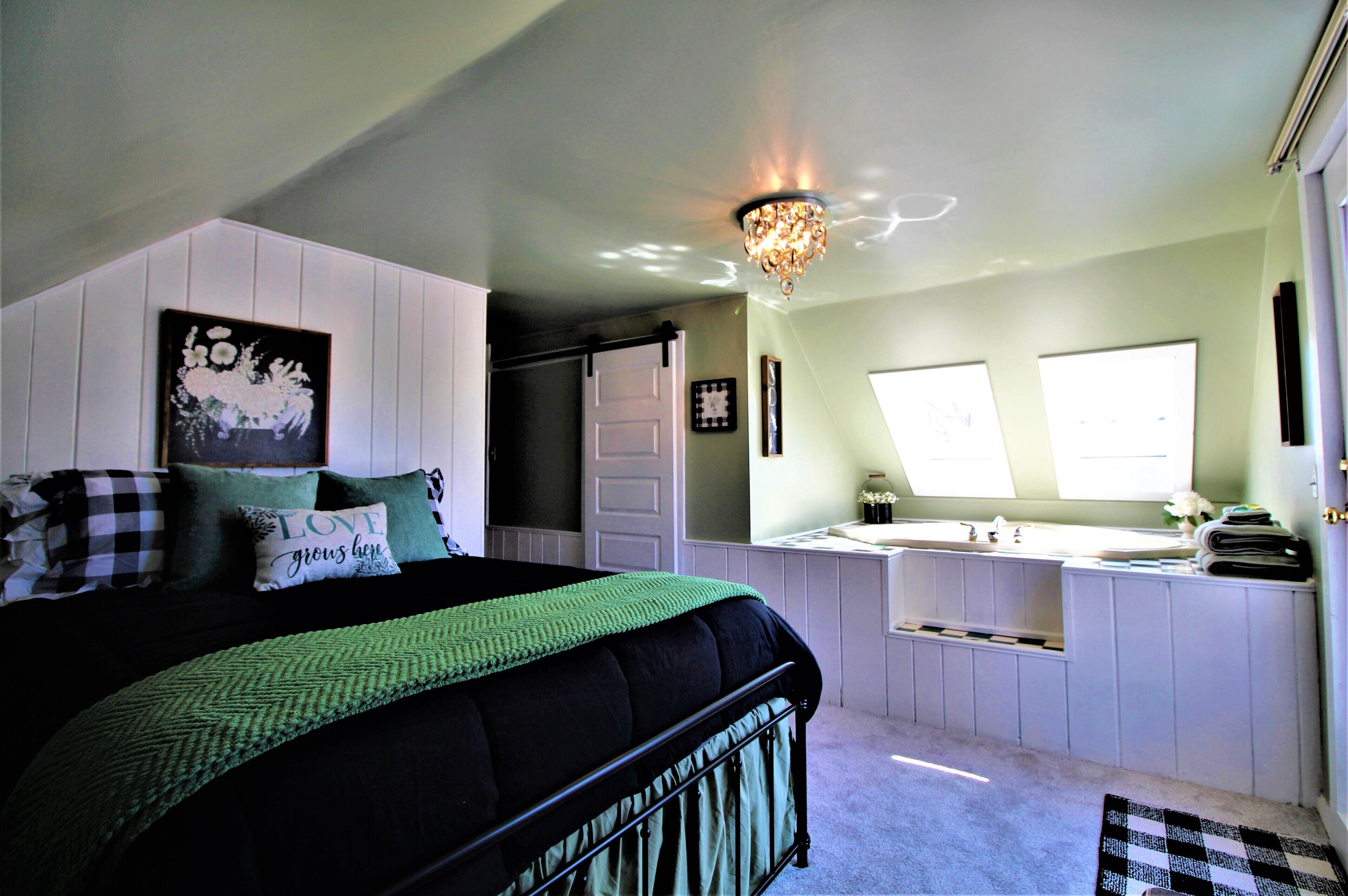 A bedroom with a bed, a nightstand, a dresser, a window, and a chandelier.