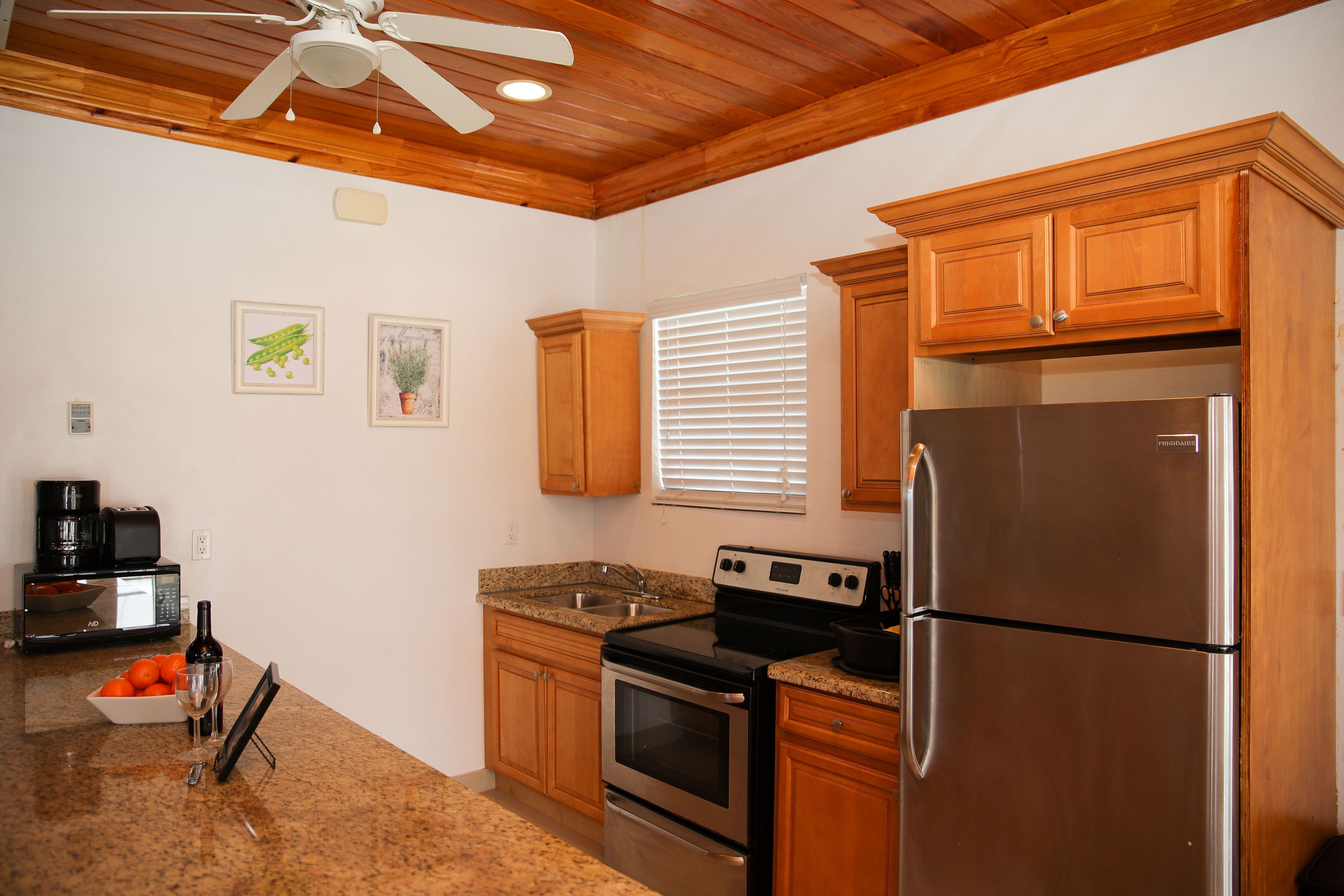 A kitchen with wooden cabinets, a stainless steel refrigerator, a microwave, and a stove.
