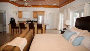 A hotel room with a large bed, a sofa, a kitchenette, and a dining area. - Tangerine Sunsets Satsuma One (Nassau)