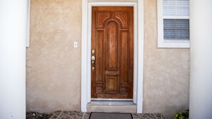 A wooden door with a white frame, set in a beige stucco wall. - Tangerine Sunsets Satsuma One (Nassau)