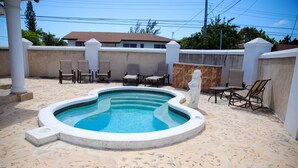 A swimming pool with a stone deck, surrounded by chairs and a statue. - Tangerine Sunsets Satsuma One (Nassau)