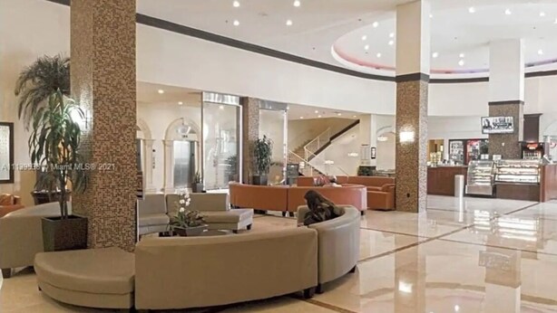 Spaziosa hall con un'area salotto a forma di curva, una scala e la reception.