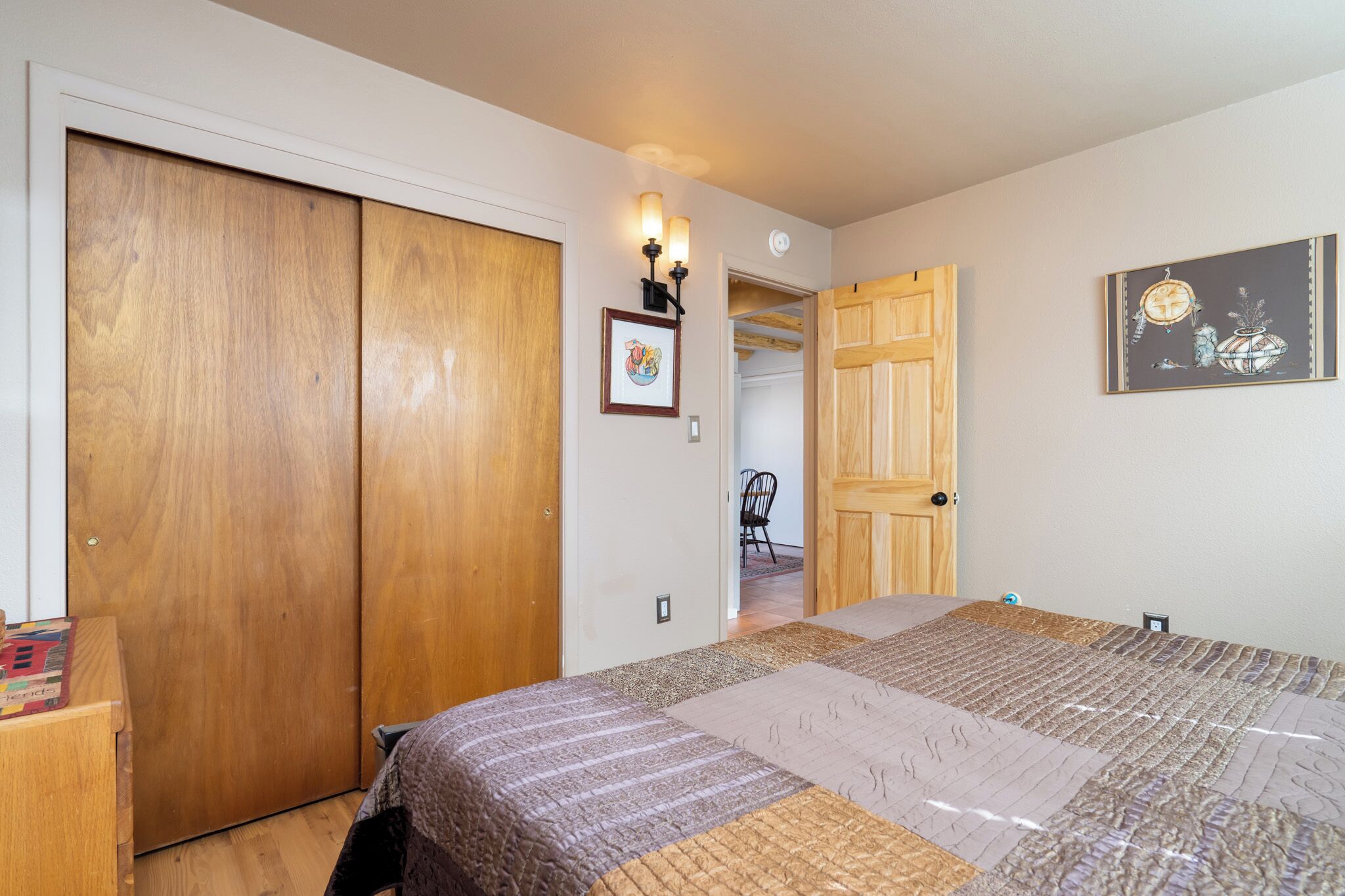Un dormitorio con una cama grande, un armario de madera y una puerta que da a otra habitación.