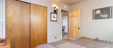 Un dormitorio con una cama grande, un armario de madera y una puerta que da a otra habitación.