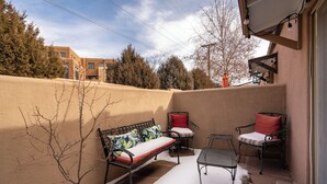 A patio with a bench, two chairs, and a small table. - Casita De Alces by Kokopelli Property Management (Santa Fe)