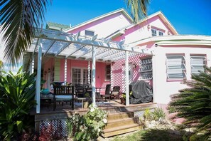 A pink house with a covered porch, outdoor seating, and a small garden.