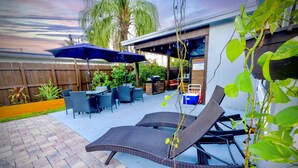 Un patio con sillones de descanso, una parrilla y un área de estar techada con sombrillas.