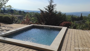 A rectangular swimming pool with a wooden deck surrounding it.