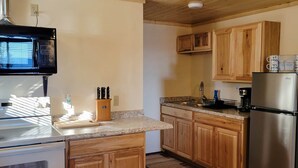 A kitchen with wooden cabinets, a stainless steel refrigerator, a microwave, and a stove.
