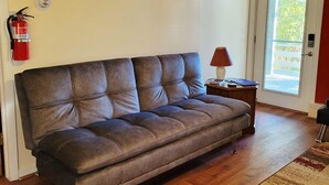 A brown leather sofa in a room with a wooden floor, a red wall, and a door with a window.