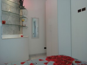 Une chambre à coucher avec un lit recouvert de pétales de rose, un miroir et une armoire.