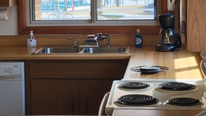 A kitchen with a window, a sink, a stove, and a coffee maker.