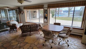 A dining area with a stone floor, a round table, and wicker chairs.