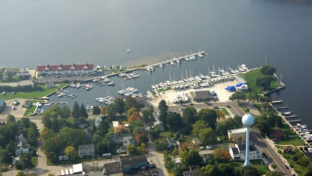 An aerial view of a marina with boats docked, a water tower, and surrounding buildings.