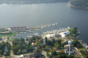 An aerial view of a marina with boats docked, a water tower, and surrounding buildings. - Marina View in the Village (Pentwater)