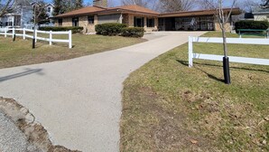 A two-story house with a stone facade, a covered porch, and a fenced yard.
