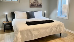 Makuuhuoneessa on suuri sänky, kaksi yöpöytää, seinään kiinnitetty lamppu, kehystetty taulu ja ikkuna.