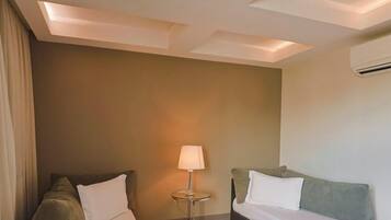 A hotel room with a bed, a nightstand, a lamp, and an air conditioning unit.