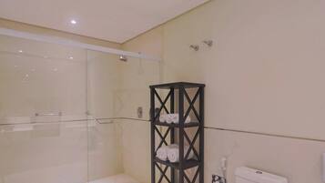 Un baño con cabina de ducha de vidrio, un toallero negro y un inodoro.