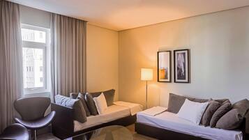 A hotel room with a bed, two bedside tables, a chair, a desk, a lamp, and two framed pictures on the wall.
