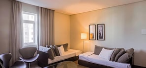 A hotel room with a bed, a desk, a chair, a lamp, and two framed pictures on the wall. - Manhattan On Floor (Curitiba)