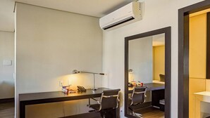 A hotel room with a bed, desk, two chairs, a desk lamp, a telephone, and a large mirror. - Manhattan On Floor (Curitiba)