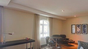 A modern living room with a dining area, a large window with curtains, and three framed pictures on the wall. - Manhattan On Floor (Curitiba)