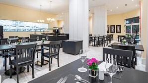 A hotel restaurant with multiple dining tables, chairs, and a bar area. - Manhattan On Floor (Curitiba)