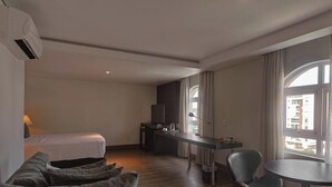 A hotel room with a bed, a desk, a chair, and a window. - Manhattan On Floor (Curitiba)