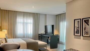 Habitación de hotel con cama, escritorio, televisor y dos cuadros en la pared.