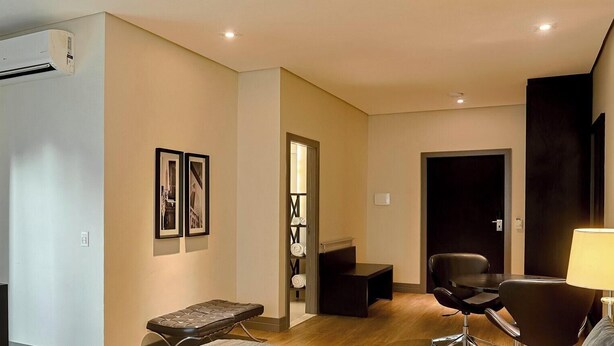 A modern hotel room with a flat-screen TV, a massage table, a desk, and a chair. - Manhattan On Floor (Curitiba)