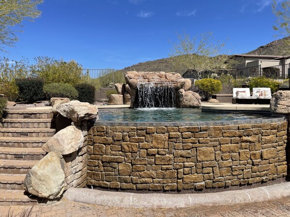 A stone pool with a waterfall feature, surrounded by a stone wall and steps.