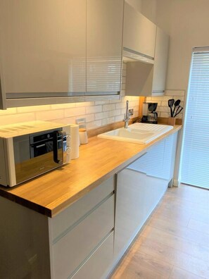 A modern kitchen with a wooden countertop, stainless steel appliances, and white cabinetry. - Luxury 2 bed Apartment Golden Triangle w Parking (Norwich)