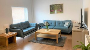 A modern living room with a grey sofa, a wooden coffee table, and a TV on a stand. - Luxury 2 bed Apartment Golden Triangle w Parking (Norwich)